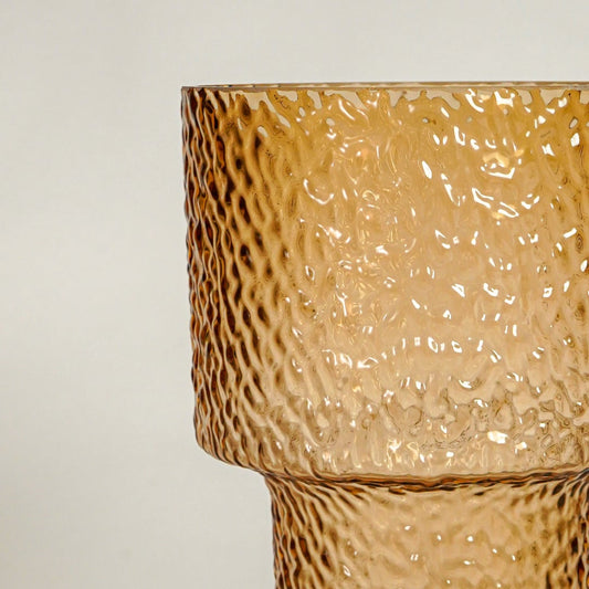 Close up view amber textured glass vase showing hammered surface glossy finish decorative glass accent for modern home styling.