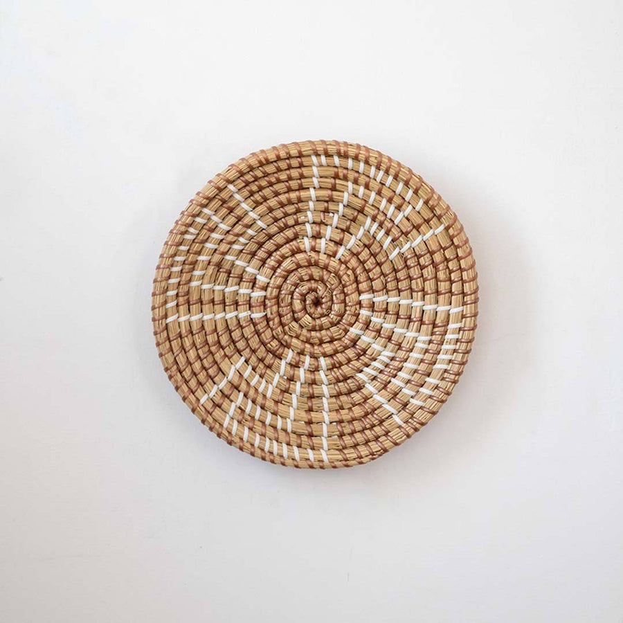 Minimalist handcrafted woven seagrass wall hanging basket decor plate featuring a brown geometric pattern on white.