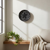 Black woven wall basket displayed above a console table for artistic contemporary wall decor and modern home interiors.