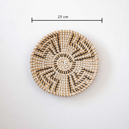 Handwoven wall basket in natural and black fiber shown with 25cm diameter for decorative wall placement.