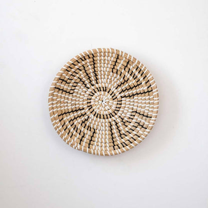 Minimalist handcrafted woven seagrass wall hanging basket decor plate featuring a beige geometric pattern on white.