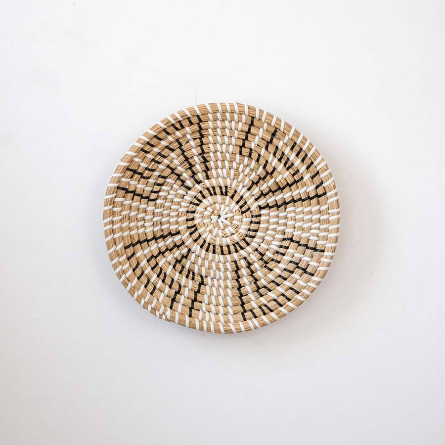 Minimalist handcrafted woven seagrass wall hanging basket decor plate featuring a beige geometric pattern on white.