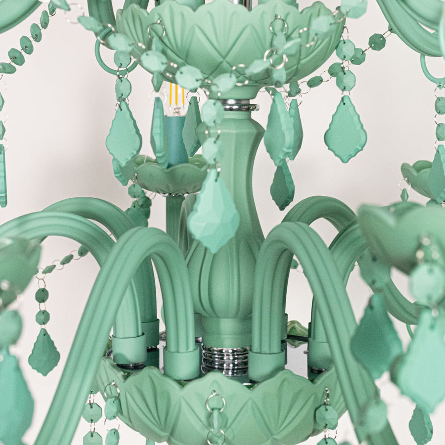 Closeup of large green crystal chandelier with detailed beads and curved arms perfect for stylish luxury ceiling decor.