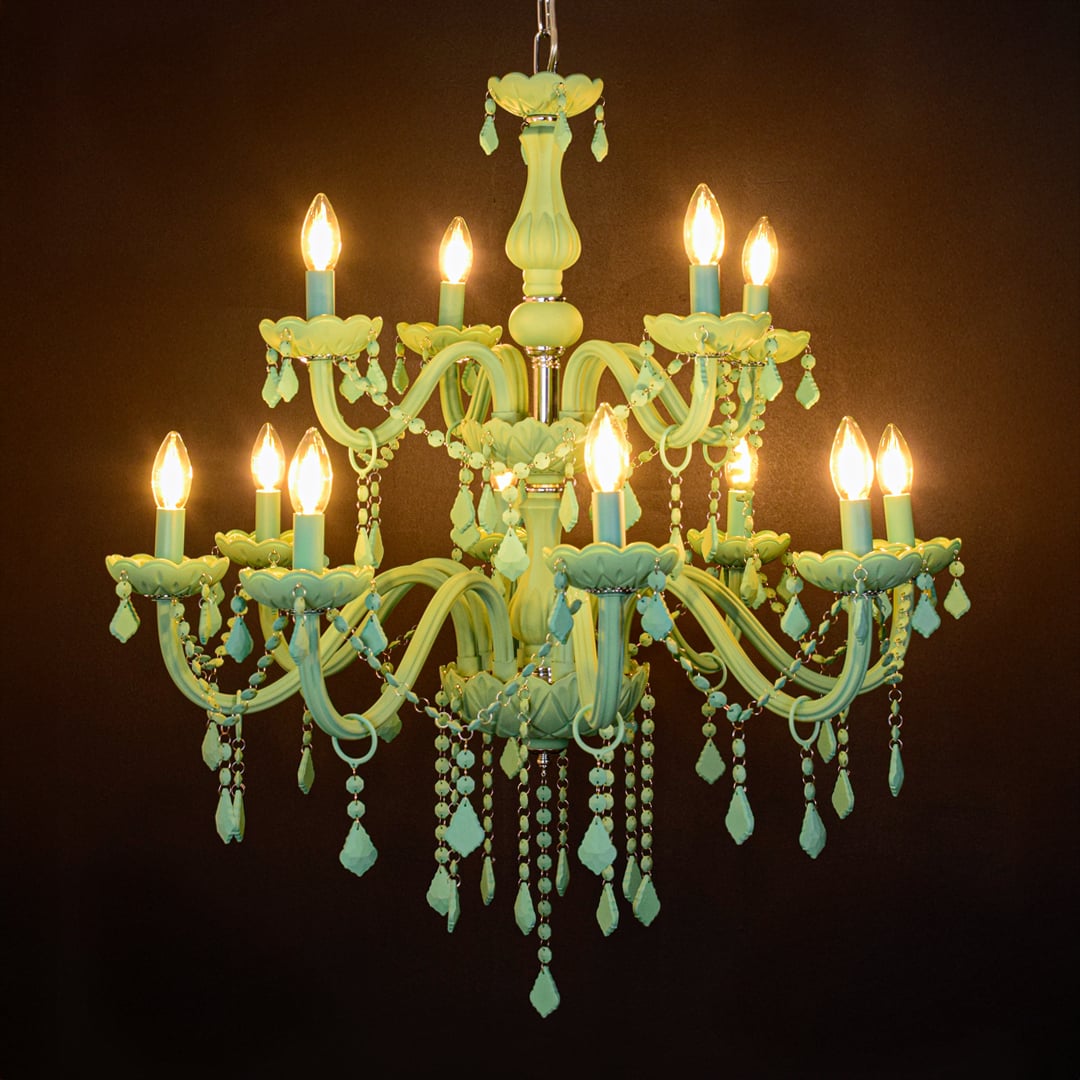 Large green crystal chandelier glowing warmly on black background creating a striking modern luxury ceiling feature.