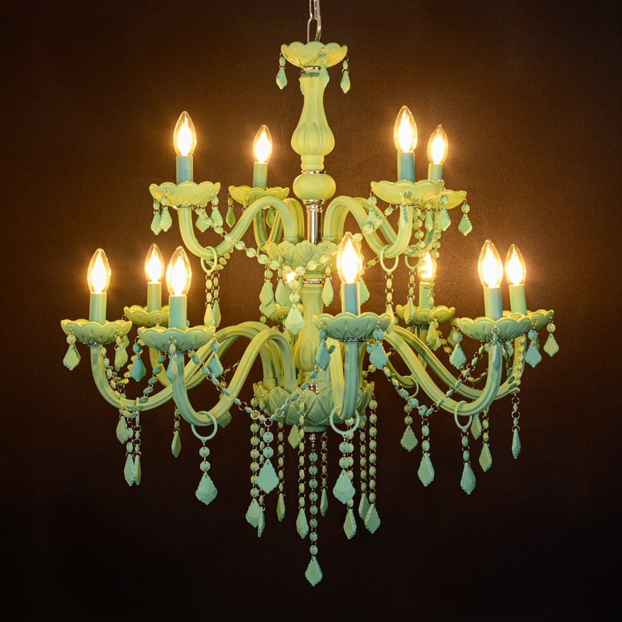 Large green crystal chandelier glowing warmly on black background creating a striking modern luxury ceiling feature.