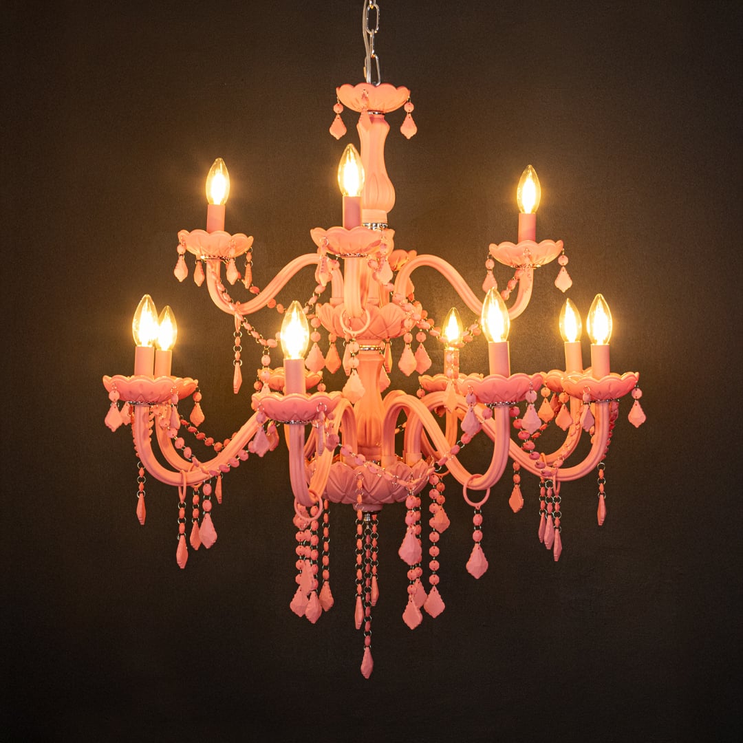 Large pink crystal chandelier glowing warmly on black background creating a striking luxury ceiling feature.