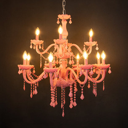 Large pink crystal chandelier glowing warmly on black background creating a striking luxury ceiling feature.