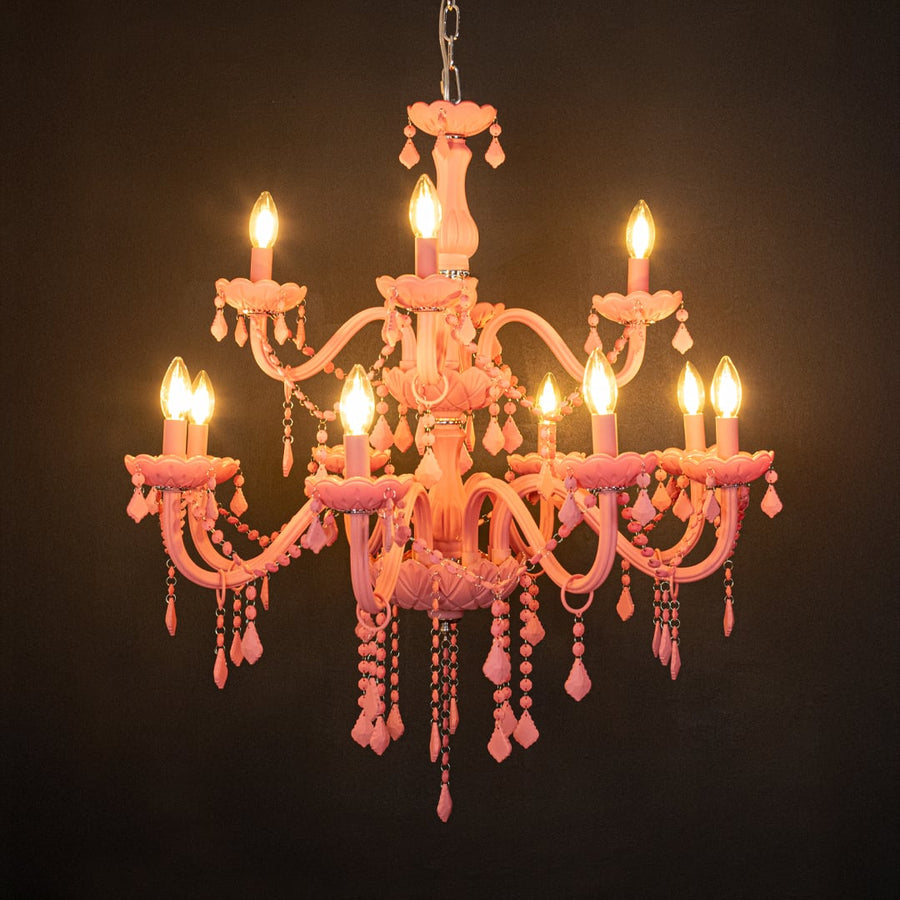 Large pink crystal chandelier glowing warmly on black background creating a striking luxury ceiling feature.