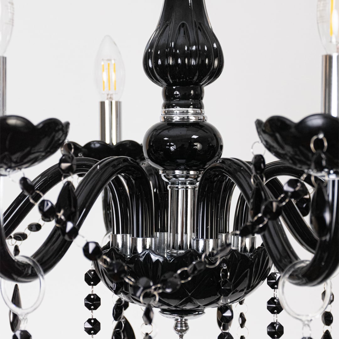 Closeup of black chandelier with crystal detailing and glossy arms showing luxury lighting design features.