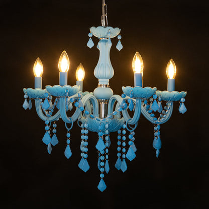 Blue crystal chandelier glowing warmly on black background creating a striking luxury ceiling feature.