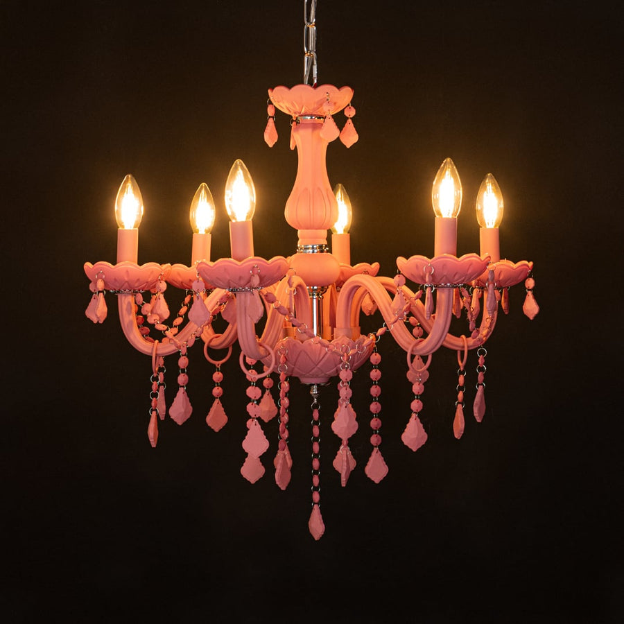 Pink crystal chandelier glowing warmly on black background creating a striking luxury ceiling feature.