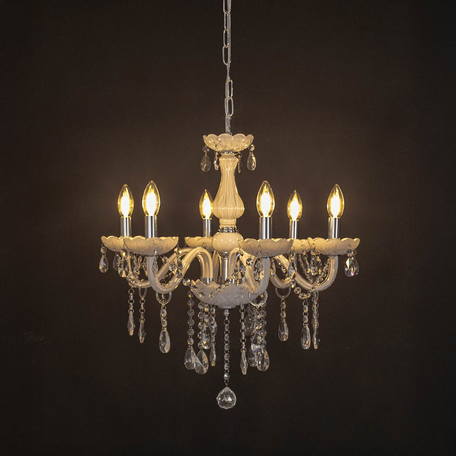 Elegant white chandelier with crystal details illuminated against black background for luxury home lighting.