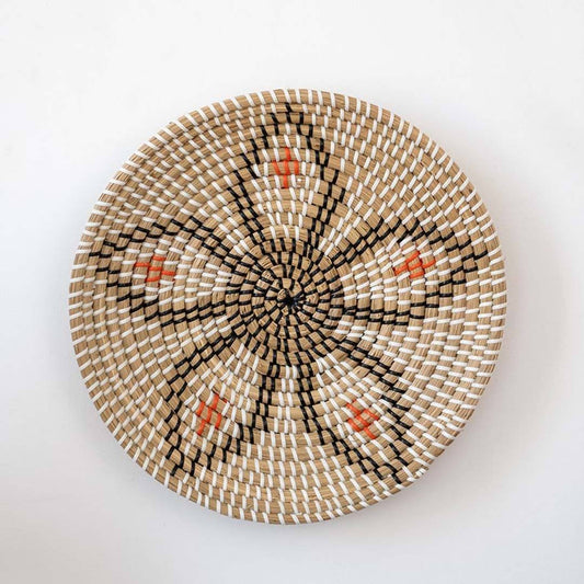Handwoven seagrass round wall basket decor in natural beige and black with floral leaf woven pattern on white background.