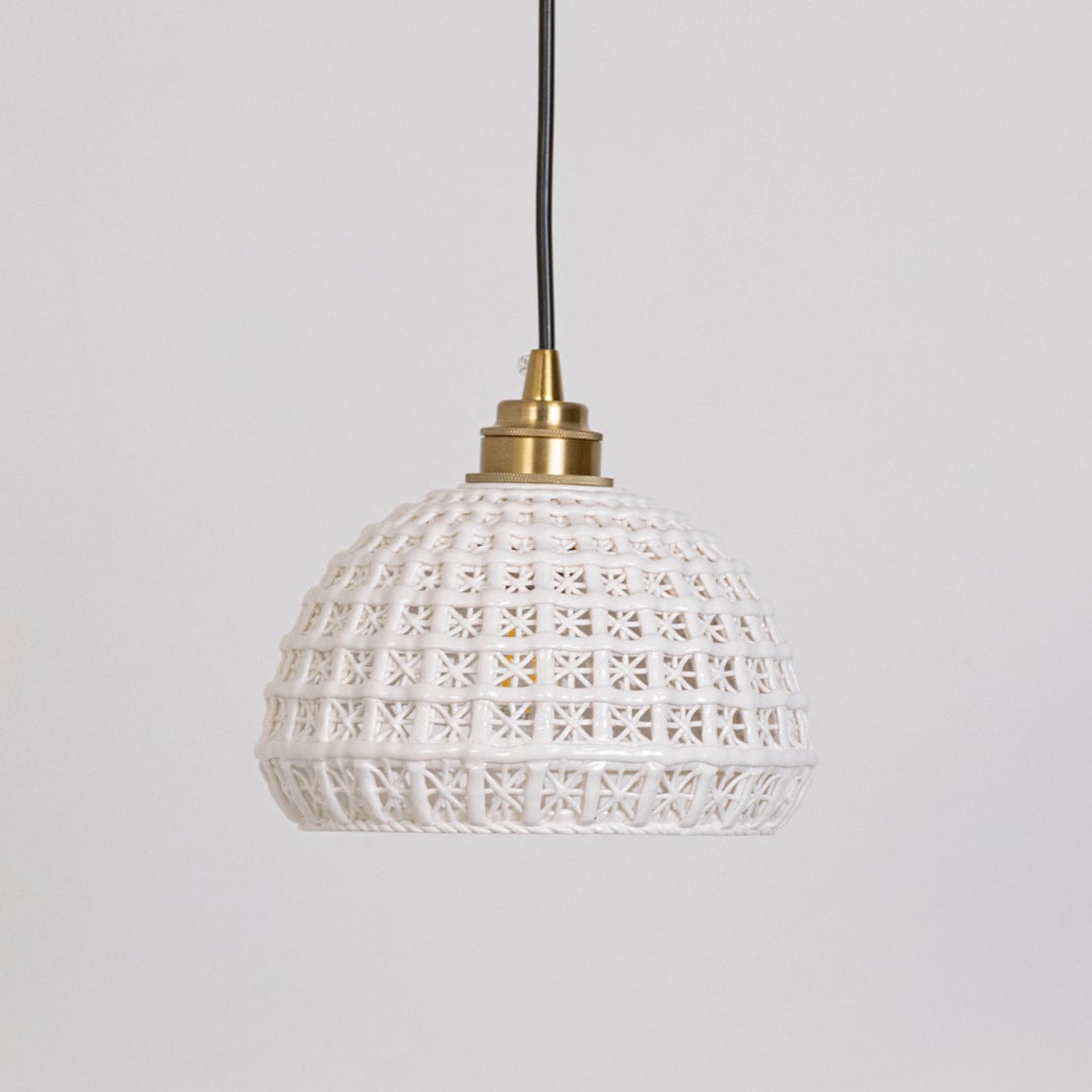 White woven pendant light displayed on a white background with lights off highlighting its woven dome shape.