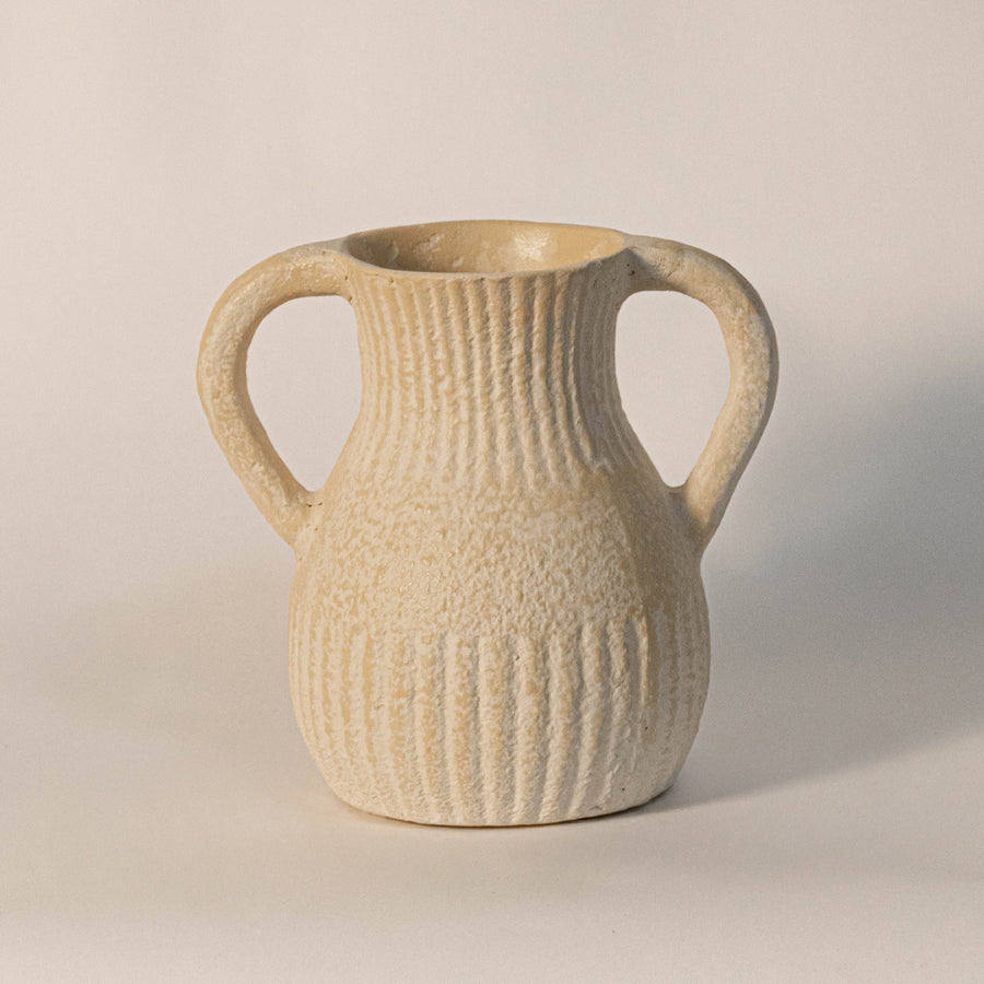 Decorative ceramic vase with dual handles in beige finish and ribbed texture for table decor or shelf styling modern home placement white background.