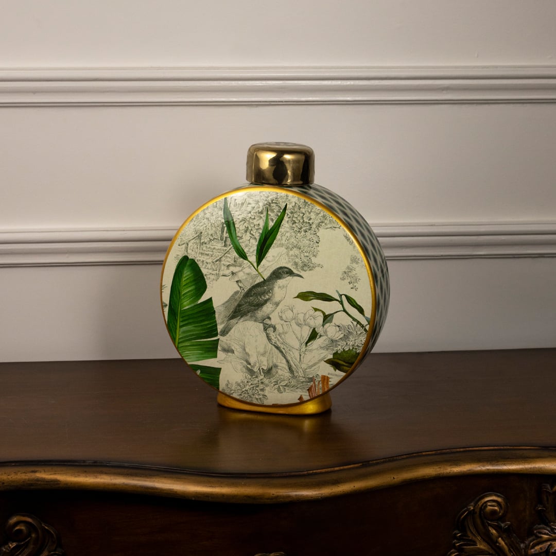 Tropical bird jar with golden detailing and botanical print featuring bird and tropical leaves on white background.