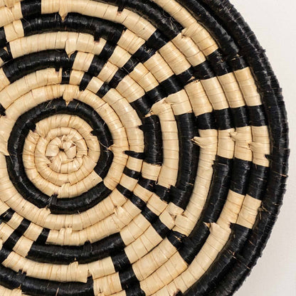 Detailed closeup of handcrafted black cream seagrass wall basket with woven geometric labyrinth pattern for artisan decor.