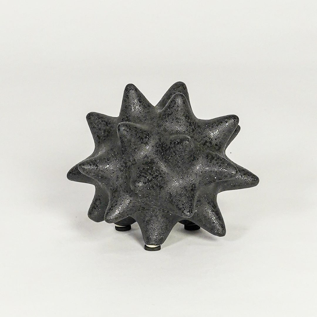 Modern black ceramic statement decor accent with starburst inspired sculpted shape for contemporary interiors.