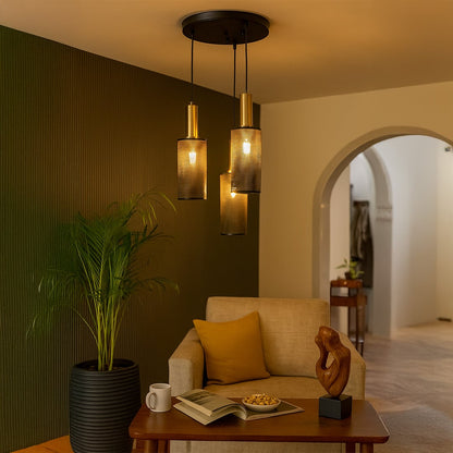 Modern three layer pendant light with black mesh shades and gold holders brightening a cozy living room corner beside a beige sofa and indoor plant.