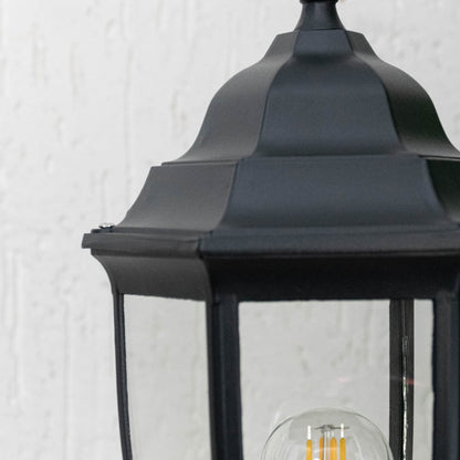 Detailed zoom view of black pillar light showcasing transparent glass frame with LED bulb for outdoor home lighting.
