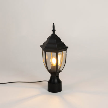 Black outdoor gate light with warm glowing bulb and clear glass shade for elegant exterior decor use.