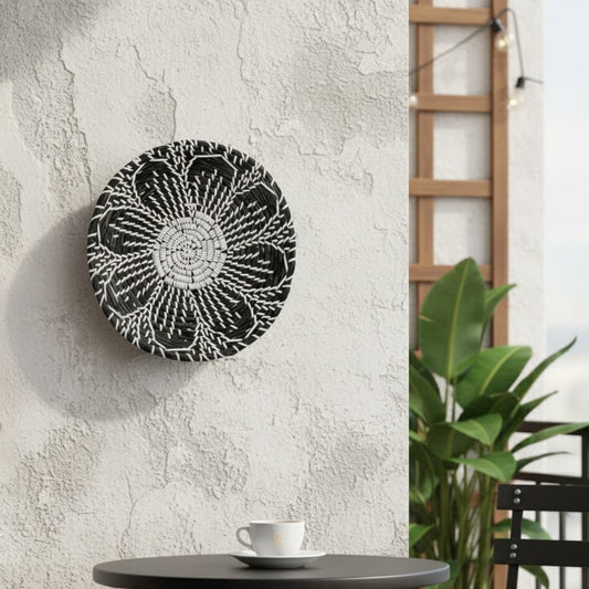 Artistic round wall decor in black and white finish mounted on textured wall adding bold contrast to modern interior decor.