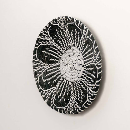 Side view of handcrafted black cream woven seagrass wall basket with detailed multi petal flower pattern for boho wall decor.