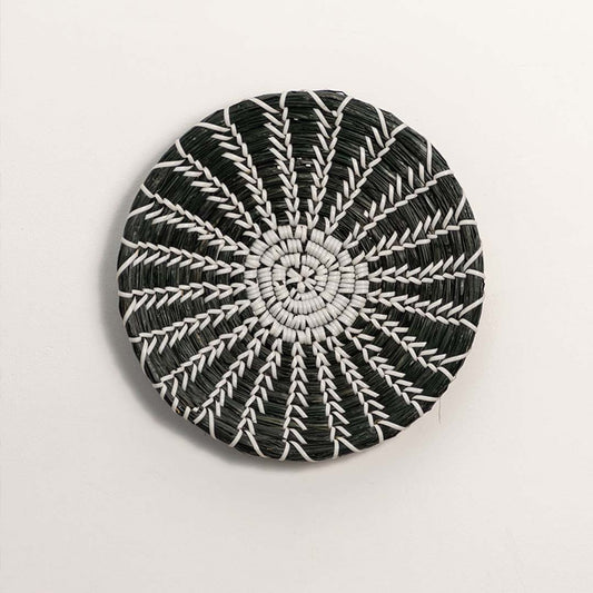 Black and white woven decorative wall basket with spiral sunburst pattern for artistic wall styling and modern home decor.