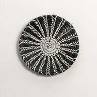 Black and white woven decorative wall basket with spiral sunburst pattern for artistic wall styling and modern home decor.
