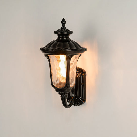 Black metal outdoor wall lantern on white background with textured water glass shade for classic entryway decor.