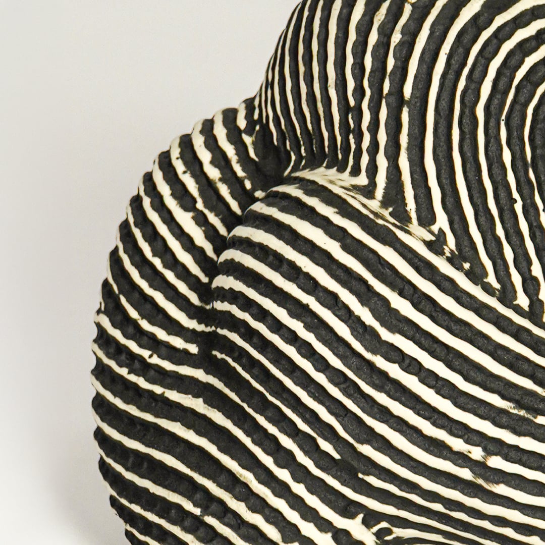 Close up view black and white striped ceramic sculpture highlighting curved organic form textured pattern and handcrafted surface detail.