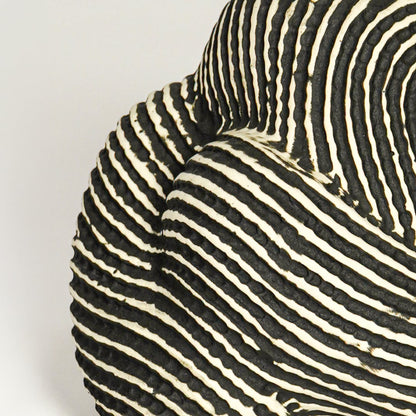 Close up view black and white striped ceramic sculpture highlighting curved organic form textured pattern and handcrafted surface detail.