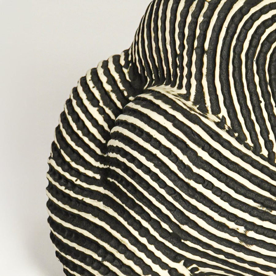 Close up view black and white striped ceramic sculpture highlighting curved organic form textured pattern and handcrafted surface detail.
