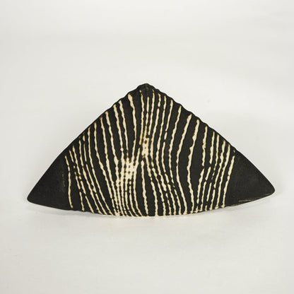 Modern black and beige ceramic triangle decor sculpture isolated on white background with bold linear design.