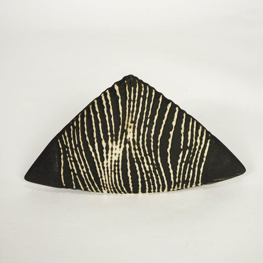 Modern black and beige ceramic triangle decor sculpture isolated on white background with bold linear design.