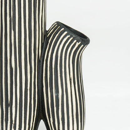 Detailed closeup of black and white striped curvy ceramic vase highlighting vertical lines and sculpted form.