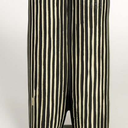 Close view of black ceramic vase showing vertical striped texture matte finish and sculptural form.