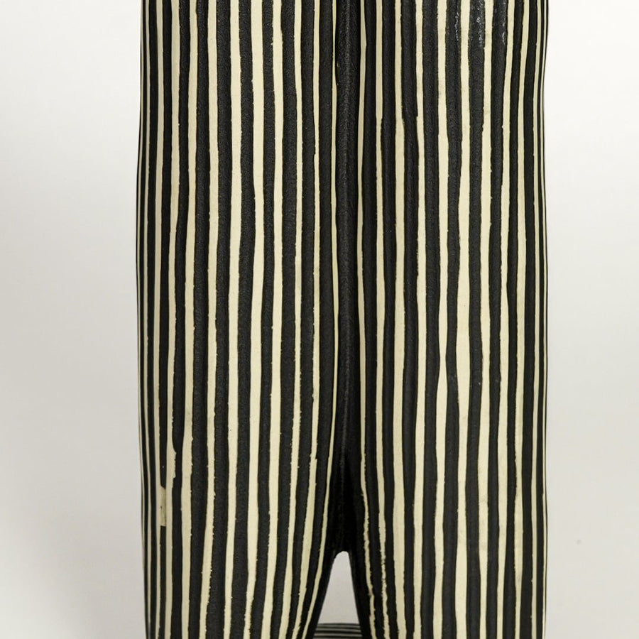 Close view of black ceramic vase showing vertical striped texture matte finish and sculptural form.