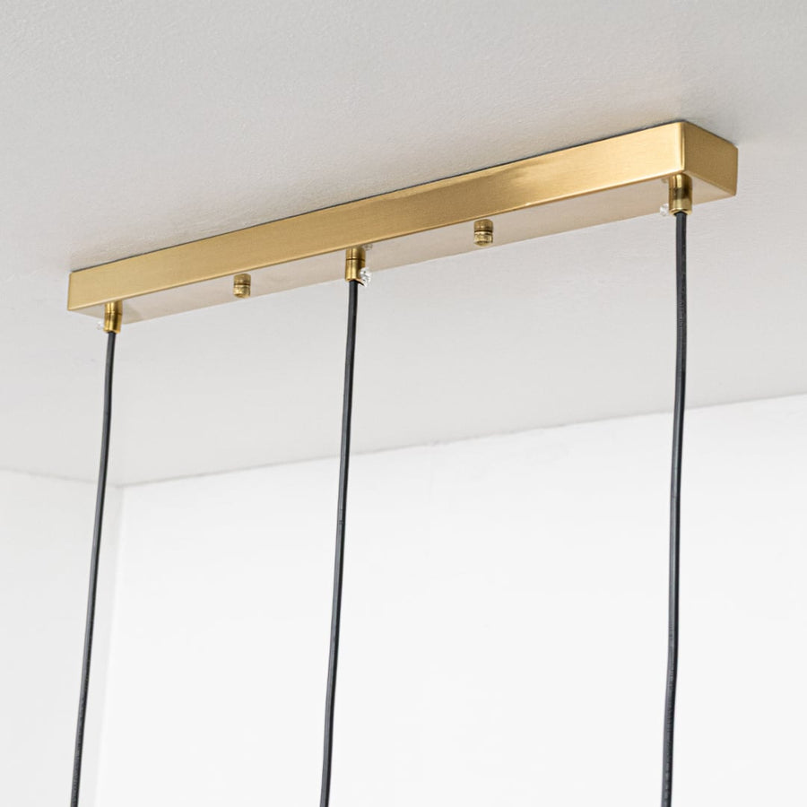 Close view of modern pendant lights with frosted globes gold stems and vibrant pink yellow and blue petals showcasing a fun decorative style.
