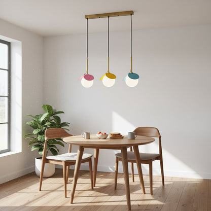 Playful modern pendant light trio with white globes and colorful petals in pink yellow and blue hanging from a gold bar creating a bright room look.