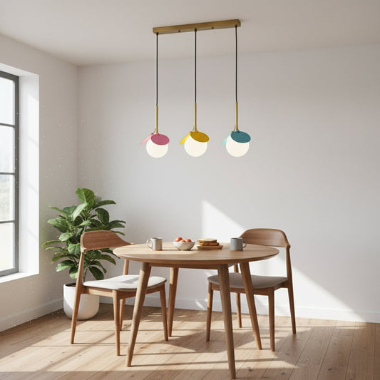 Playful modern pendant light trio with white globes and colorful petals in pink yellow and blue hanging from a gold bar creating a bright room look.
