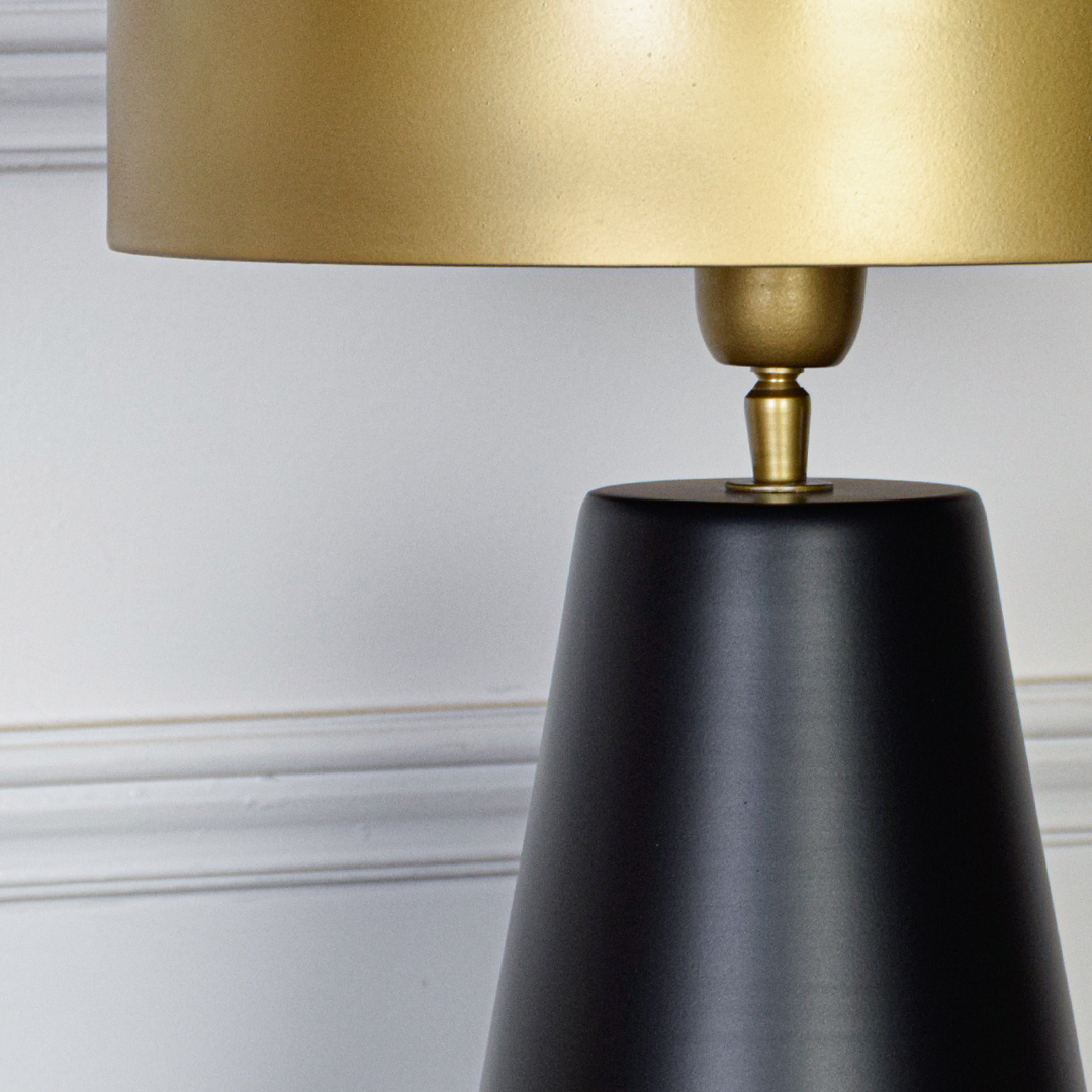 Table lamp closeup showing brushed gold shade smooth connector and matte black base with refined texture and elegant contemporary detailing.