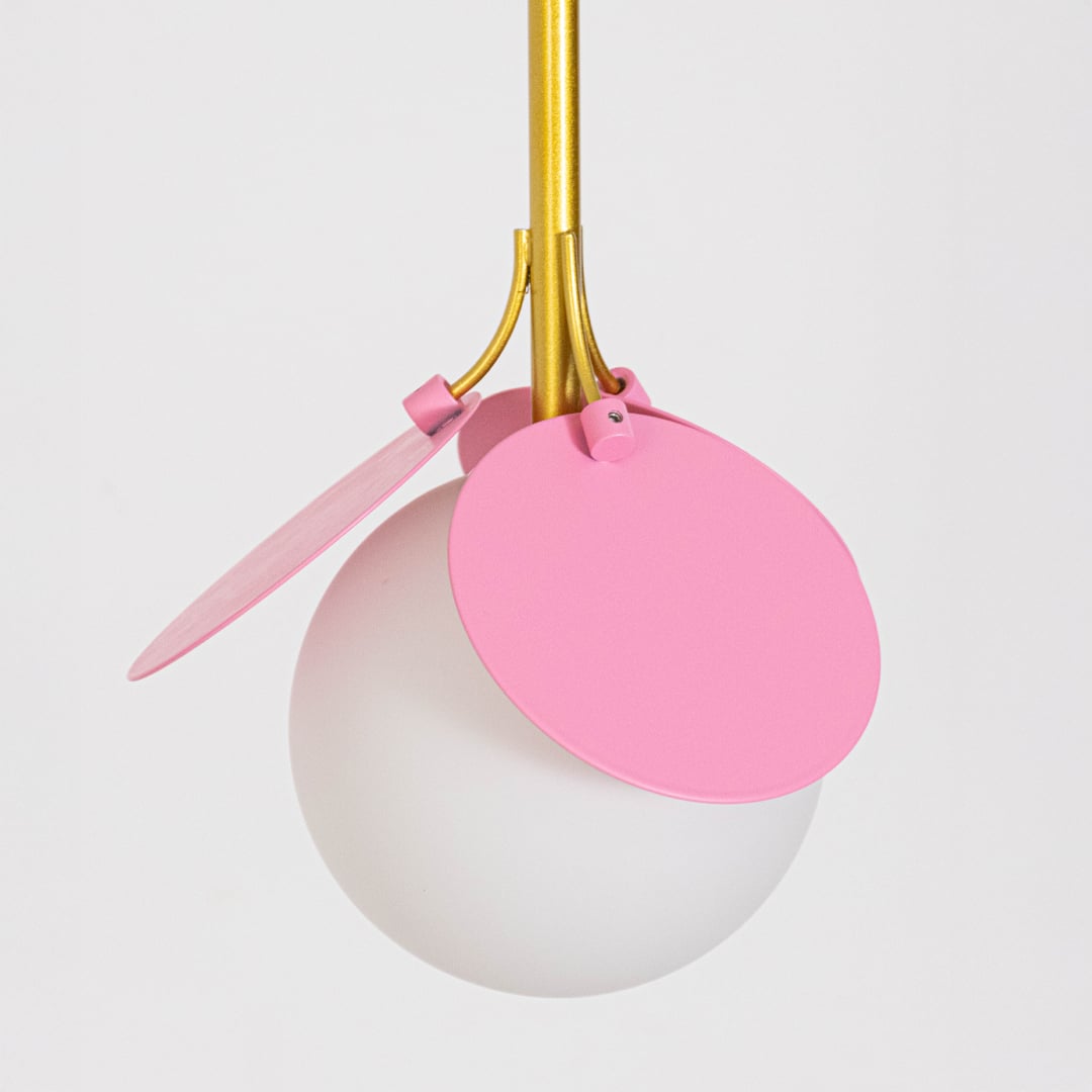 Decorative triple pendant light with frosted globe shades and colorful petal accents suspended from a black ceiling bar on a clean white background.