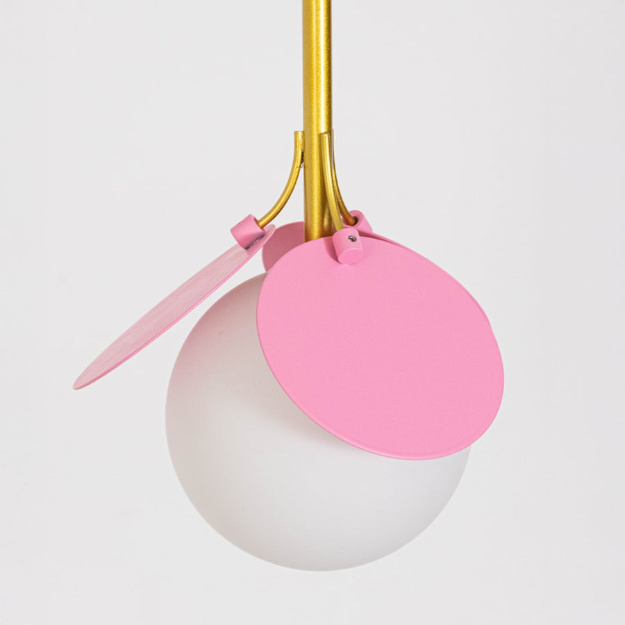 Decorative triple pendant light with frosted globe shades and colorful petal accents suspended from a black ceiling bar on a clean white background.