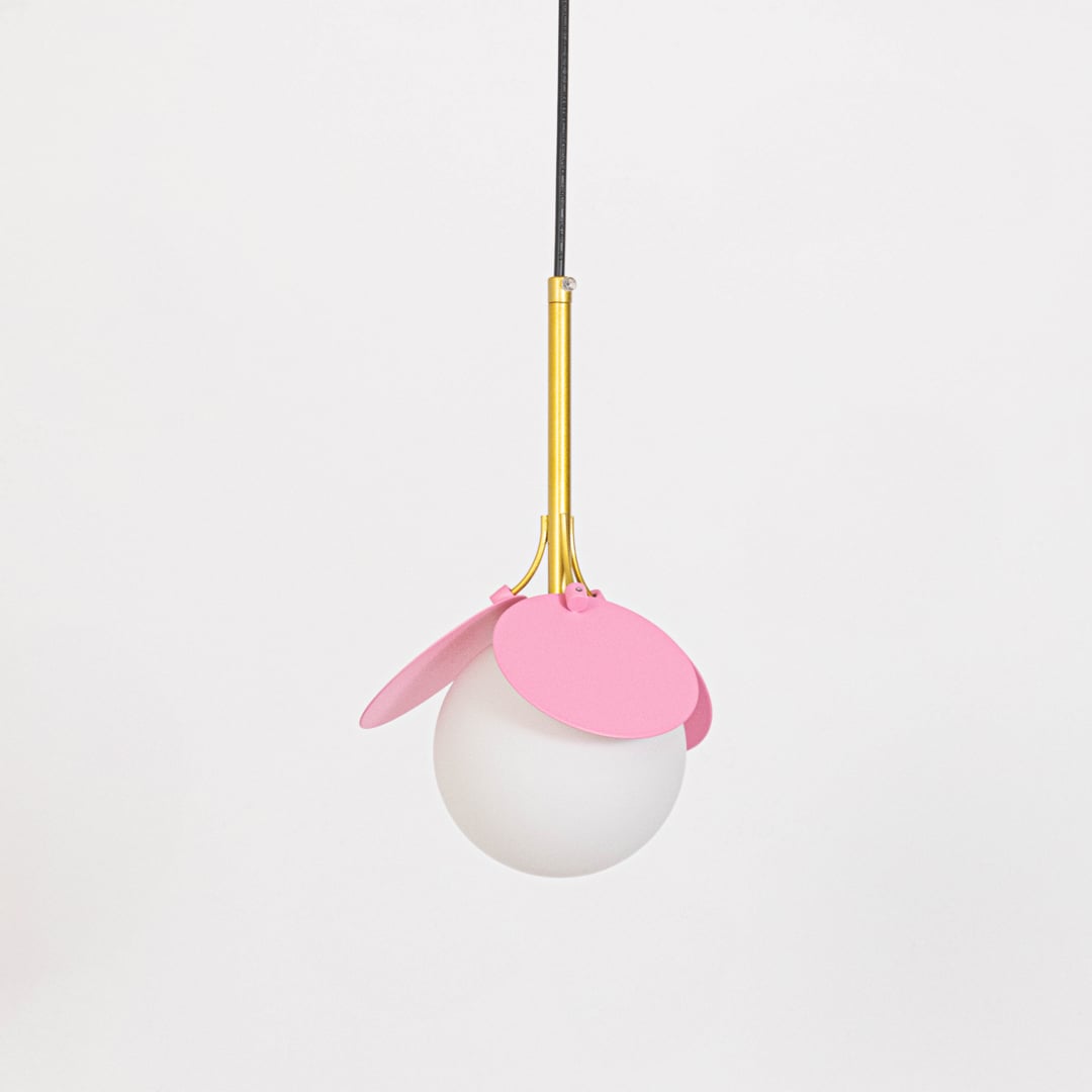 Pendant light with pink shade and frosted glass globe shown switched off with gold holder on plain white background.