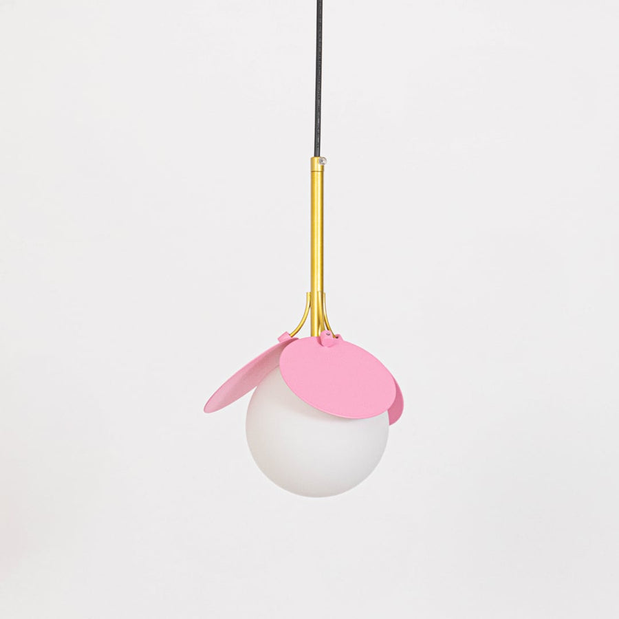 Pendant light with pink shade and frosted glass globe shown switched off with gold holder on plain white background.