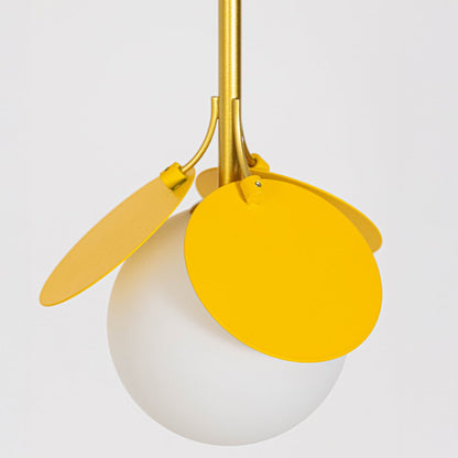 Closeup view of modern pendant light with frosted glass globe yellow metal petal accents and gold stem shown light off on white background.