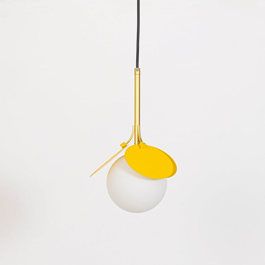 Pendant light with yellow frame and frosted glass globe shown off on white background for home interiors.