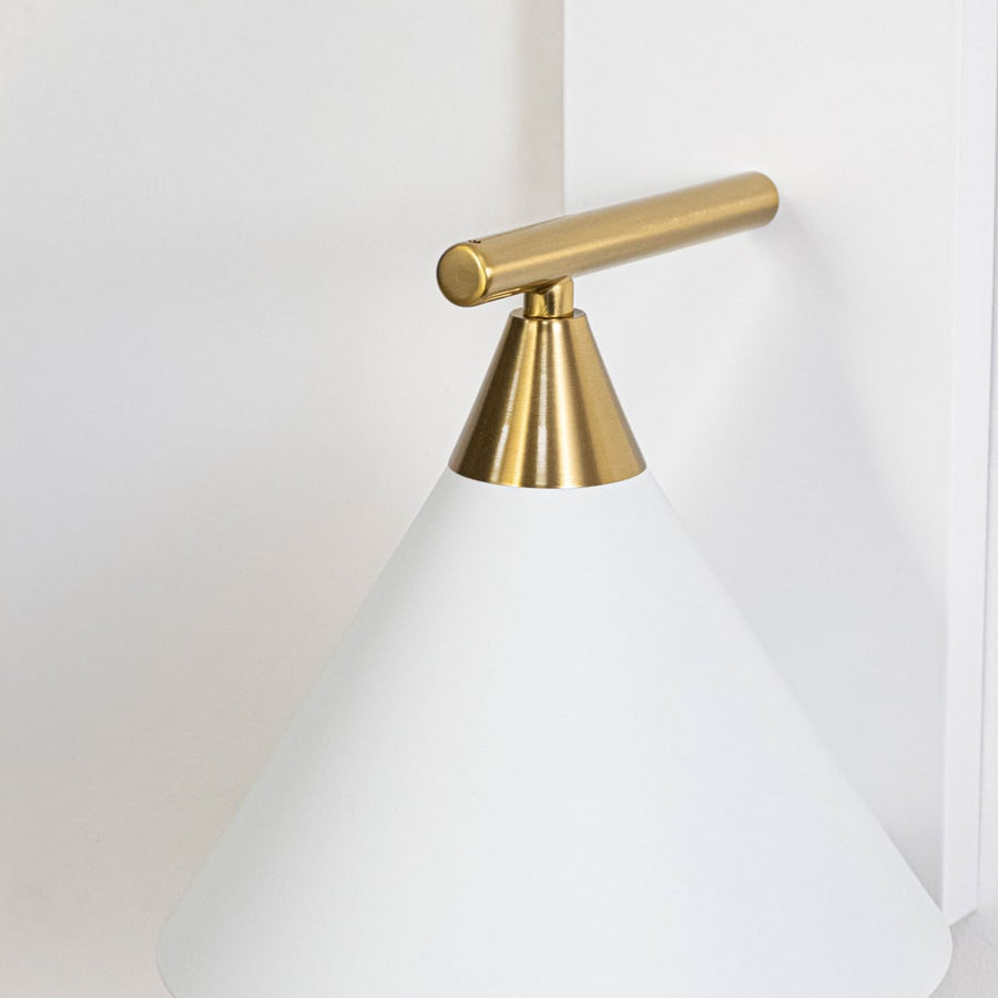 Detailed closeup of matte white metal cone shade and brushed brass gold arm on contemporary minimalist wall sconce fixture.