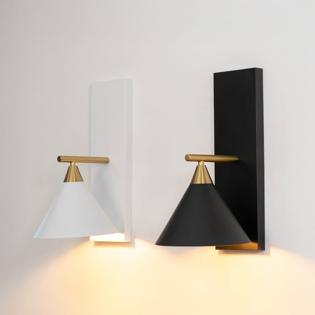 Set of modern white cone shade wall lights with brass gold arms illuminated together on pristine white background display.